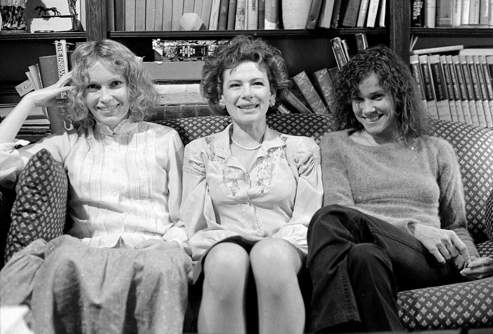 Three women sitting on a couch, smiling.