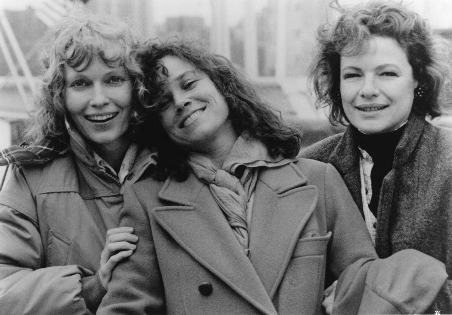 Three women smiling in black and white.